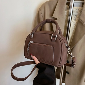 Dark brown matte bowling bag with silver chain and adjustable strap in a warm setting