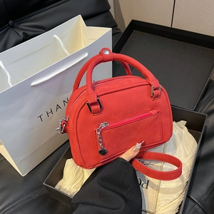 Red matte Boston bag with heart pendant chain and dual straps on gift packaging