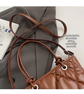 Close-up of brown quilted tote bag showing fine stitching and metallic eyelets