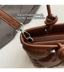 Detail of silver metal hooks and detachable strap on quilted brown leather tote bag