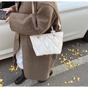 Detail of white quilted tote bag with diamond stitching texture and sleek shoulder strap