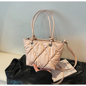 Close-up of quilted beige tote bag with soft padding and silver metal buckle detail