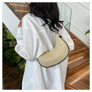 Rear view of a model wearing the woven crescent shoulder bag with black leather strap