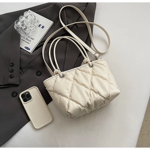 Close-up of quilted cream tote bag with puffy diamond texture and silver metal hardware