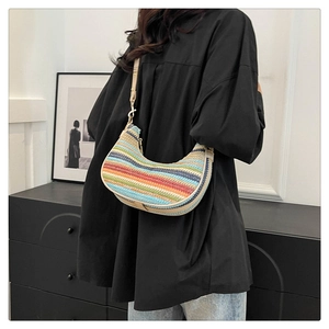 Detail of colorful striped straw crescent bag with beige leather strap on shoulder