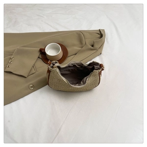 Detailed interior of the straw half-moon bag showing brown lining and zipper pocket