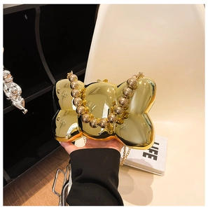 Elegante borsa clutch in acrilico a forma di fiocco con finitura dorata e manico a perle