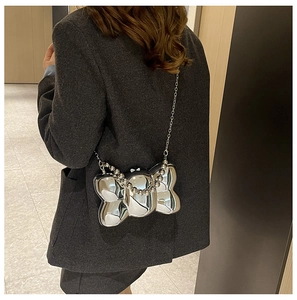 Borsa a fiocco in acrilico specchiato argento con catena e manico di perle sul modello