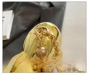 Dettaglio macro della borsa a cuore in acrilico dorato con catena e finiture metalliche