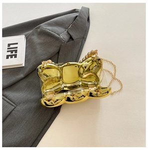 Dettaglio della borsa clutch a fiocco dorata che mostra l'interno e la catena in metallo