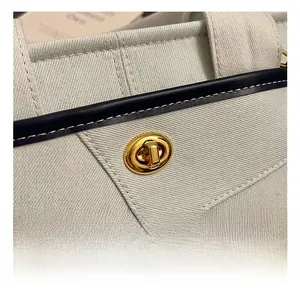 Detailed macro view of the golden metal twist lock and stitching on a canvas tote bag