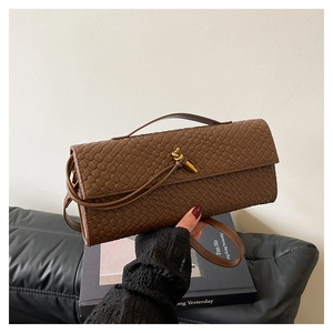 Detail shot of brown woven leather bag featuring a gold knot clasp and textured finish