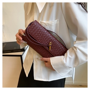 Close-up of wine red woven leather baguette bag with a decorative gold ball metal clasp