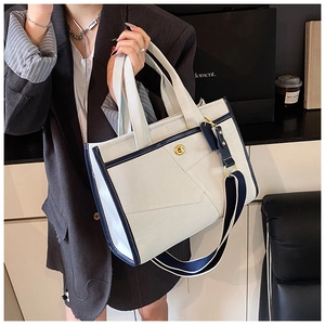 Detail of canvas tote bag with blue leather trim and golden metal twist lock closure
