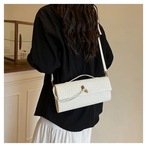 Close-up of white woven shoulder bag with gold metal twist lock and slim strap
