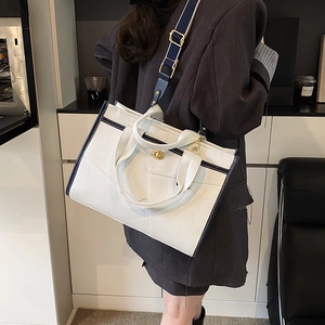 Detailed back view of a canvas tote bag featuring navy blue trim and adjustable shoulder strap