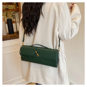 Detail of dark green woven texture bag with gold twist lock and adjustable shoulder strap
