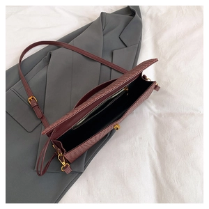 Detailed view of burgundy woven crossbody bag showing inner pocket and gold hardware