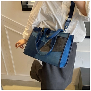 Detail of blue denim patchwork tote bag showing adjustable strap and golden hardware