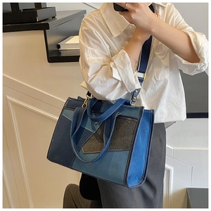 Detail of patchwork denim tote bag showing wide fabric strap and golden metal buckle