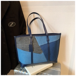 Sac cabas en jean patchwork bleu avec lanières en cuir sur une valise en métal