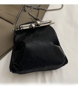 Detail of black glossy textured leather bag with large metal ball clasp and silver chain