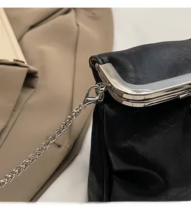 Close-up of glossy pleated leather bag with metallic clasp and silver chain detail