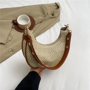 Striped woven straw crescent bag with brown leather trim and golden rivets for beach vacations
