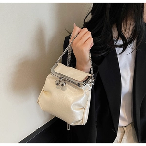 Detail of creamy white pleated crossbody bag with silver kiss-lock closure and metal chain