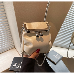 Close-up of beige mini bucket bag with metallic frame closure and delicate chain strap