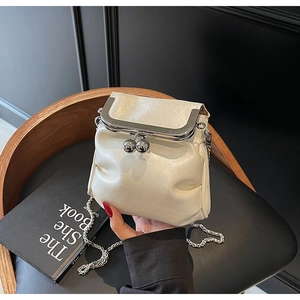 Detail of cream pleated cloud bag featuring metal spherical lock and silver chain