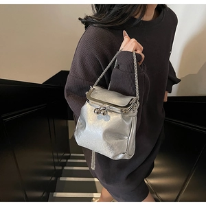 Detail of silver pleated crossbody bag featuring retro metal frame and chain strap