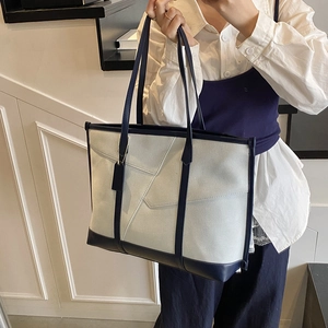 Gros plan d'un grand sac cabas bicolore en toile grise et détails en cuir bleu
