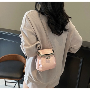 Pink pleated crossbody bag with silver clasp and chain shown on model in a casual setting