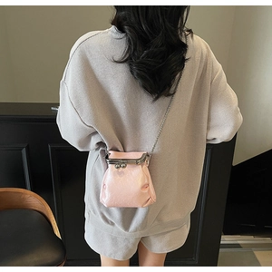 Detail of pink mini chain crossbody bag with metallic clasp worn over the shoulder