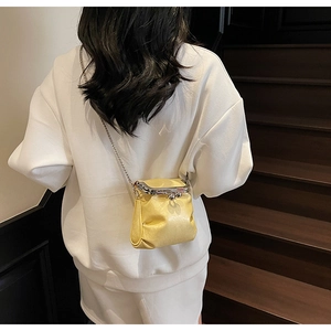 Detail of yellow pleated leather crossbody bag with vintage metal clasp and silver chain