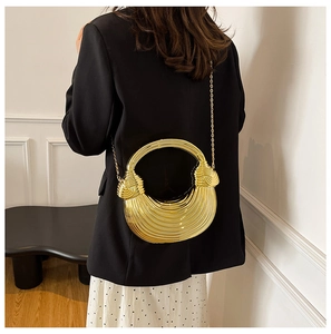 Detailed view of golden acrylic shell bag with striped texture and metal chain strap