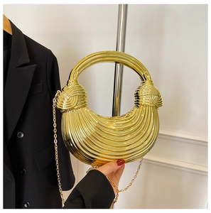 Detail view of gold acrylic shell bag with metallic stripes and elegant ring handle