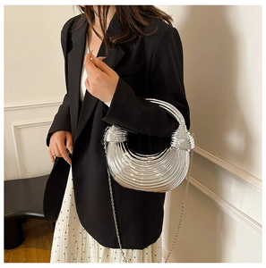 Detailed view of silver acrylic shell bag with striped texture and chain strap