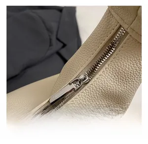 Close-up of premium cream pebble grain leather texture and silver polished metal zipper