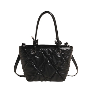 Modern black quilted tote bag with decorative knot handle and crossbody strap
