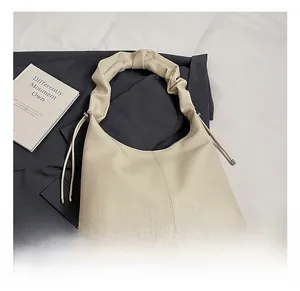 Detail of hobo bag featuring pleated cloud-style handle and lychee grain texture
