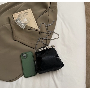 Mini retro black leather bag with silver chain and kiss-lock next to a phone for size comparison