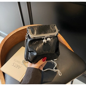 Detail of black pleated crossbody bag featuring silver ball clasp and metal chain strap