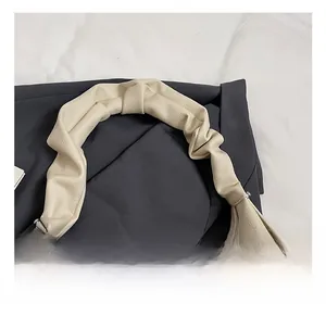 Close-up of beige pebble leather handbag featuring a unique pleated knotted handle design