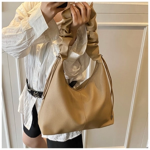 Detail of khaki leather tote bag with ruched handle and side drawstring on model