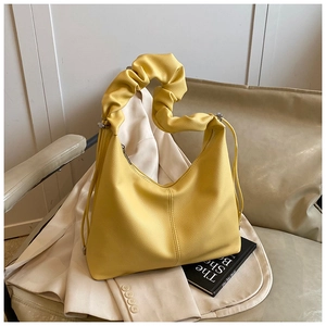 Detail of yellow baguette bag with scrunched handle and lychee texture on blazer
