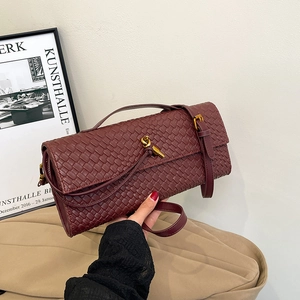 Elegant burgundy woven baguette bag with a gold knot clasp and slim shoulder strap
