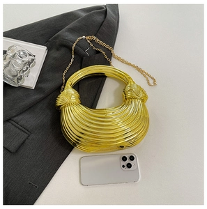 Detailed view of a gold textured shell bag featuring a metal ring handle and chain strap