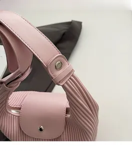 Detail of pink pleated handbag showing silver metal buckle and premium leather texture